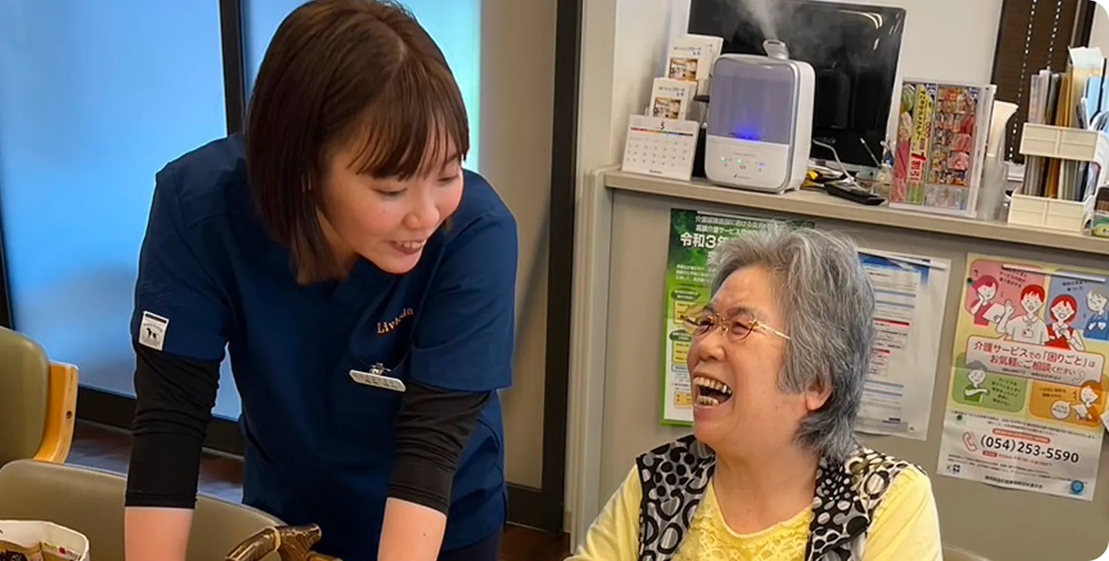 “利用者さんと”職員が笑顔で会話をしている様子